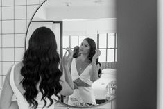 a woman standing in front of a mirror brushing her teeth