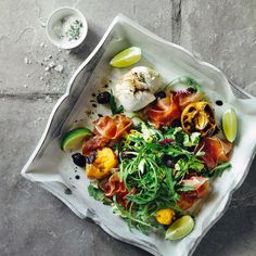 a white plate topped with lots of food on top of a cement floor next to a cup