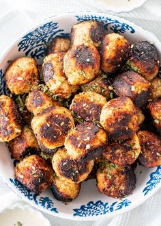 a white bowl filled with meatballs on top of a blue and white table cloth