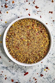 a white bowl filled with granola on top of a marble counter next to spices