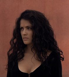 a close up of a person wearing a black shirt and long curly hair with no bra