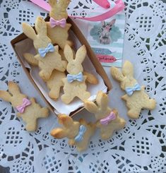 some bunny cookies are in a box on a doily with a pink bow tie