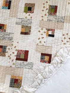 a close up of a quilt on a bed with white sheets and pillowcases