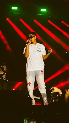 a man standing on top of a stage holding a microphone in front of red and green lights