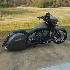 a black motorcycle parked on top of a cement road next to a grass covered field