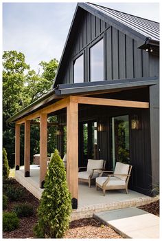 a black house with two chairs on the front porch and one sitting area in the back