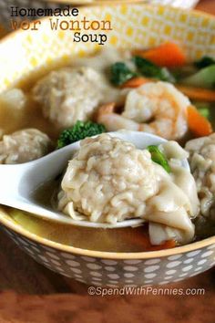 a bowl filled with dumplings and vegetables on top of a wooden table