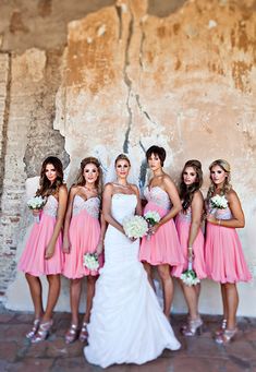 a group of women standing next to each other in front of a wall with peeling paint