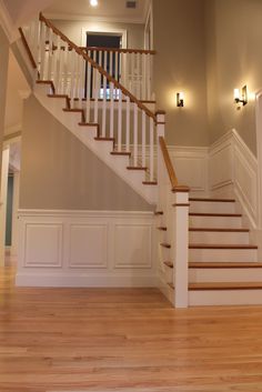 an empty room with wooden floors and white railings on the second floor is lit by recessed lights