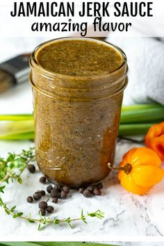 a jar filled with some sort of food on top of a white counter next to vegetables