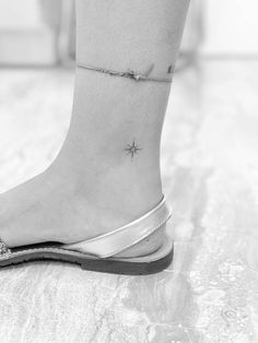 a woman's foot with a tiny star tattoo on her left ankle, and a silver sandal