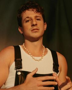 a man wearing a white shirt and black suspenders holding a cell phone in his hand