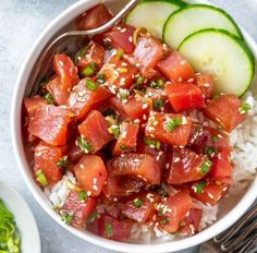 a white bowl filled with rice, cucumber and sashimi on top of it