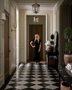 a woman in a black dress is standing on a checkered floor with her hands on her hips