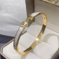 These Are Highly Polished Fashion Titanium Stainless Steel Gold Plated Pieces That Will Last A Lifetime. It Is Corrosion And Scratch Resistant And Hypoallergenic. The Bangle Is An Oval Shape That Sits Perfectly On The Wrist With The H Or Always On Top. The H/Front Are Set In A White Mother Of Pearl Style Tone. Outside Circumference Of Bracelet Is Approximately 19cm Brand New Gold Tone Color White Stainless Steel Bangle Bracelets, White Stainless Steel Bangle Bracelet, White Stainless Steel Jubilee Bracelet, White Metal Oyster Bracelet, Luxury White Stainless Steel Bracelets, Luxury White Stainless Steel Bracelet, Adjustable White Bangle, White Stainless Steel Jewelry For Formal Occasions, White Stainless Steel Formal Bracelets