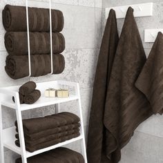 towels are hanging on the wall next to a rack with folded brown towels in it