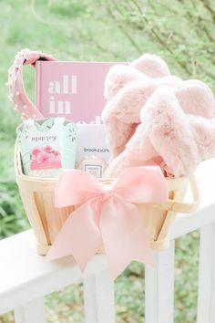 a pink teddy bear sitting on top of a basket filled with baby items next to a book