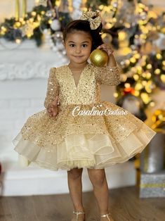 Introducing the Glamorous Gold Rihanna Dress for Baby Girls Elevate your baby girl's style with our exquisite Gold Rihanna Dress, a knee-length, voluminous ensemble that radiates brilliance, perfect for any special occasion. This resplendent dress is a captivating choice, designed to make your little one feel like a princess. The Gold Rihanna Dress features a stunning interplay of fabrics, with dazzling sequins adorning the entirety of the gold base. The long sleeves and V-shaped neckline add a touch of sophistication, creating a regal look that will transform your daughter into a little princess. The dress's enchanting silhouette is complemented by a charming and adorable hair accessory, adding a touch of sweetness to the overall look. Each Gold Rihanna Dress is a unique masterpiece, tail