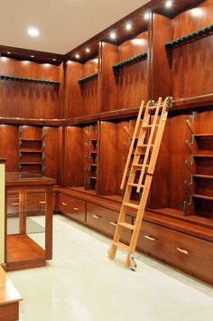 a ladder leaning up against the wall in a room filled with wooden shelves and drawers