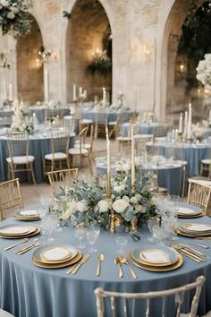 the tables are set with blue linens and gold place settings