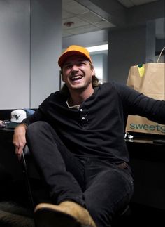 a man sitting in an office chair with a bag on his lap and smiling at the camera