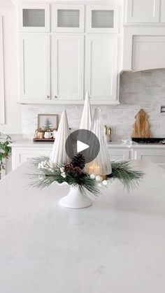 a kitchen with white cabinets and an island in the center is decorated with evergreen cones