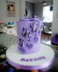 a purple cake with flowers and butterflies on it