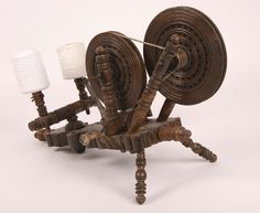 an old spinning wheel with two spools on it and a small white lamp next to it