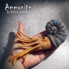 a hand holding an octopus doll with a knitted hat on it's head