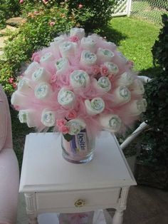 a vase filled with pink flowers sitting on top of a table next to a chair