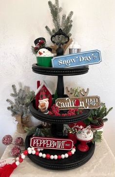 a three tiered tray with christmas decorations on it and snow day signs above the top