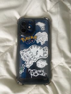 a phone case with pokemon stickers on it sitting on a white sheet covered bed