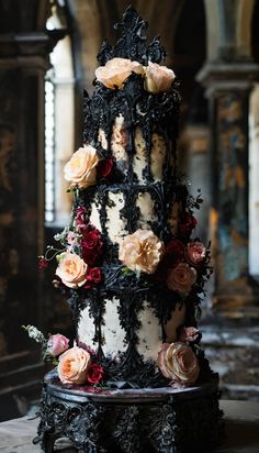 an elaborately decorated cake with flowers on it's sides and black icing