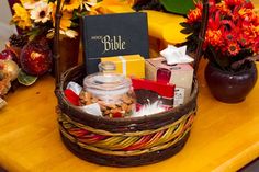 a basket filled with lots of different items on top of a wooden table next to flowers