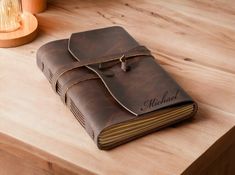 a brown leather journal sitting on top of a wooden table