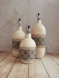 three ceramic jugs sitting on top of a wooden table next to each other,