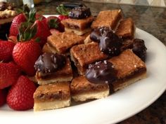 a white plate topped with lots of desserts and strawberries on top of a table