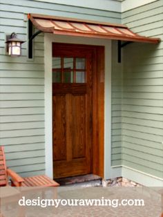 two wooden benches sitting in front of a door on the side of a house with an awning over it