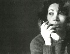 a black and white photo of a woman with her hand on her chin looking to the side