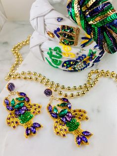 two pieces of jewelry sitting on top of a white counter next to a scarf and necklace