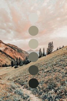 a field with trees and mountains in the background under a cloudy sky that has circles on it