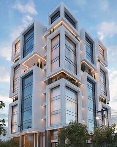 a large white building with lots of windows and lights on it's sides at dusk