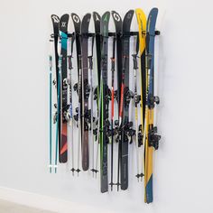 there are many skis hanging on the wall and in front of it is a pair of ski poles