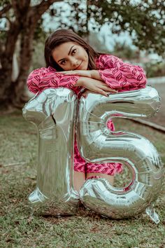 a young woman is posing for a photo in front of the number five balloon with her hands on her chest