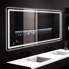 a bathroom with two sinks and a large mirror on the wall above it that is illuminated