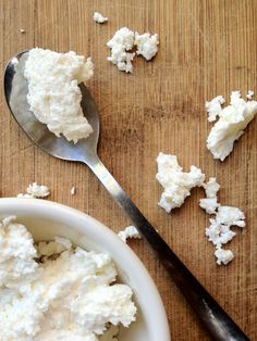 homemade raw goat cheese in a white bowl with a spoon next to it on a wooden table