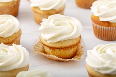 cupcakes with white frosting sitting on a table