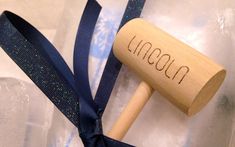 a wooden mallet with the word lincaad written on it and blue ribbon