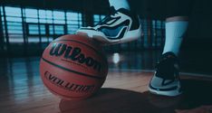 a person standing next to a basketball on top of a hard wood floor