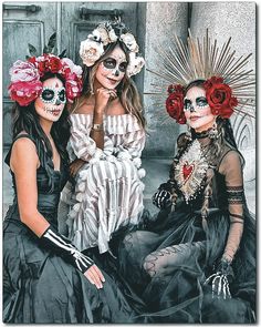 three women in skeleton makeup sitting next to each other with flowers on their heads and hands